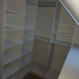 Krystian wojtas Meble Wojtas - Biała, pusta garderoba z półkami i drążkiem na ubrania, dopasowana do skosu dachu.