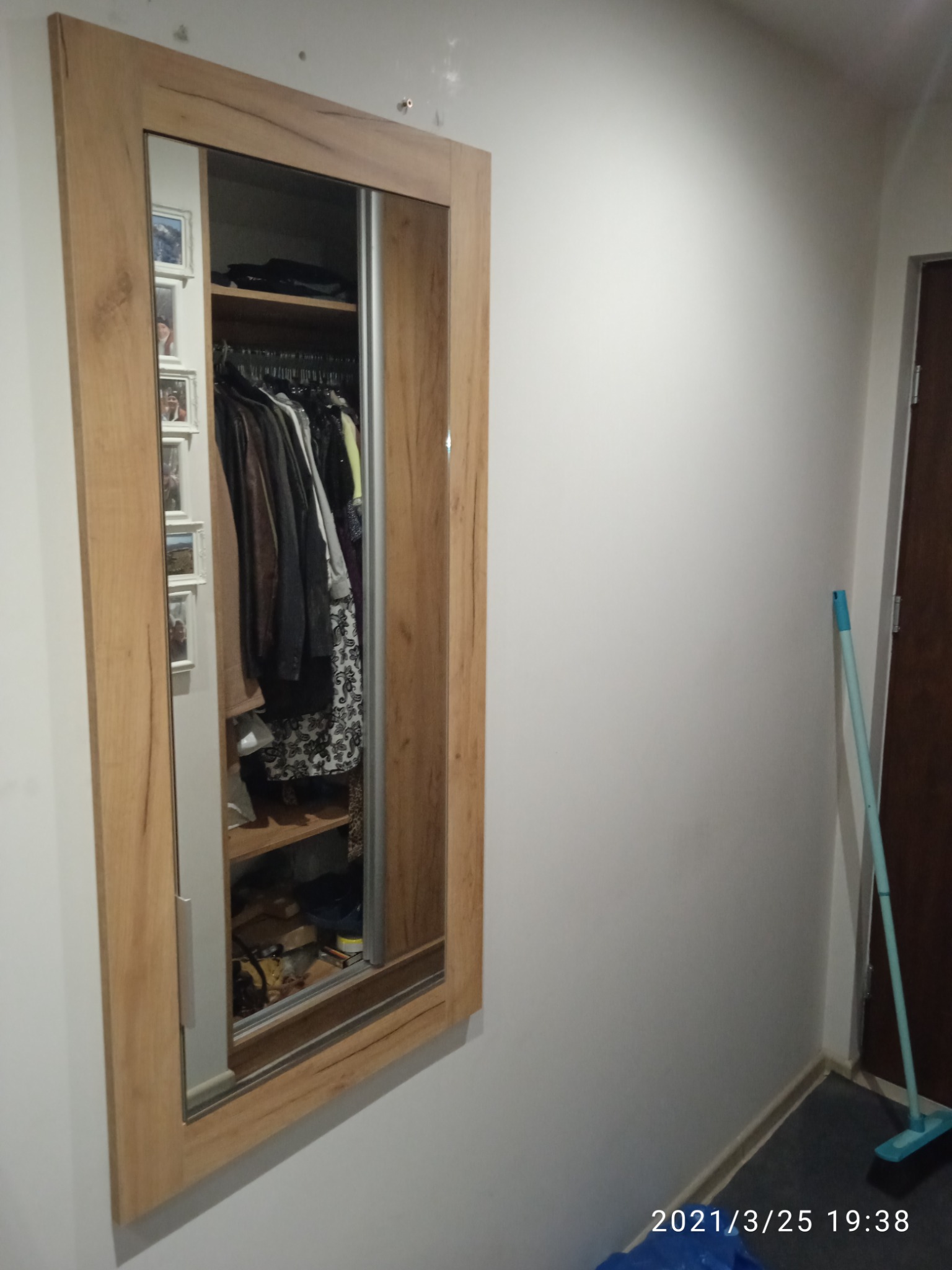 Wbudowana szafa z przesuwnymi drzwiami z lustrem w Ostrowie Wielkopolskim, ukazująca zawartość garderoby: ubrania na wieszakach i półkach.