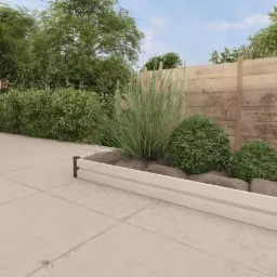 Podwyższona grządka z roślinami ozdobnymi, otoczona betonową nawierzchnią i drewnianym ogrodzeniem, z logo Garden Steel w lewym dolnym rogu.