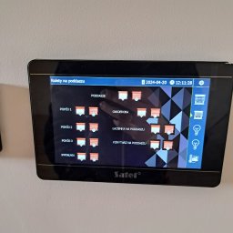 IPINSTAL Usługi Elektryczne Paweł Świstek - Ekran dotykowy systemu zarządzania domem z interfejsem sterowania roletami w różnych pomieszczeniach, ustawiony na 20 kwietnia 2024, godzina 12:11, wyświetlający logo firmy Satel.