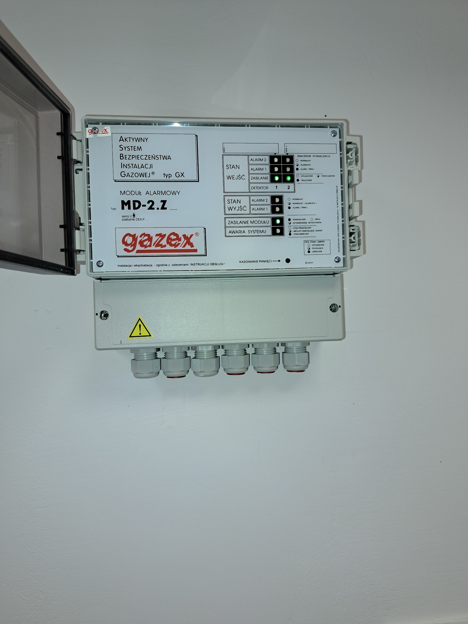 Otwarta obudowa modułu alarmowego MD-2.Z firmy Gazex, z widocznymi diodami sygnalizacyjnymi stanu, wejść, wyjść i zasilania, oraz złączami kablowymi u dołu.