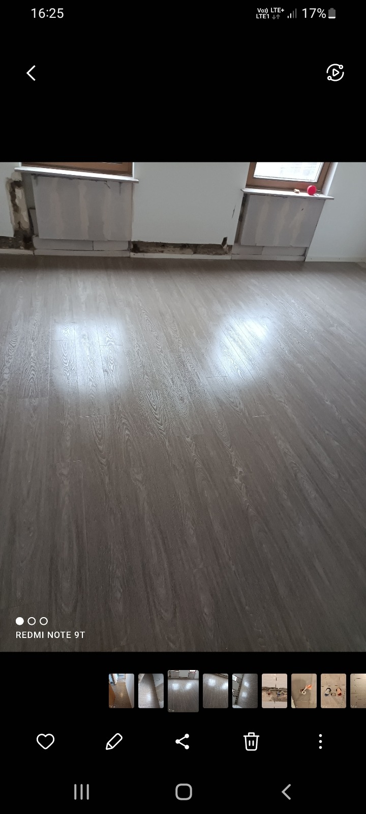 Ułożona podłoga z paneli w pokoju z oknami, fragment ściany z niedokończonymi pracami wykończeniowymi.