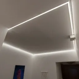 Nowoczesne oświetlenie sufitowe LED w minimalistycznym stylu, zrealizowane w mieszkaniu w Warszawie, widoczne z perspektywy podłogi, z elementami dekoracyjnymi na ścianie.