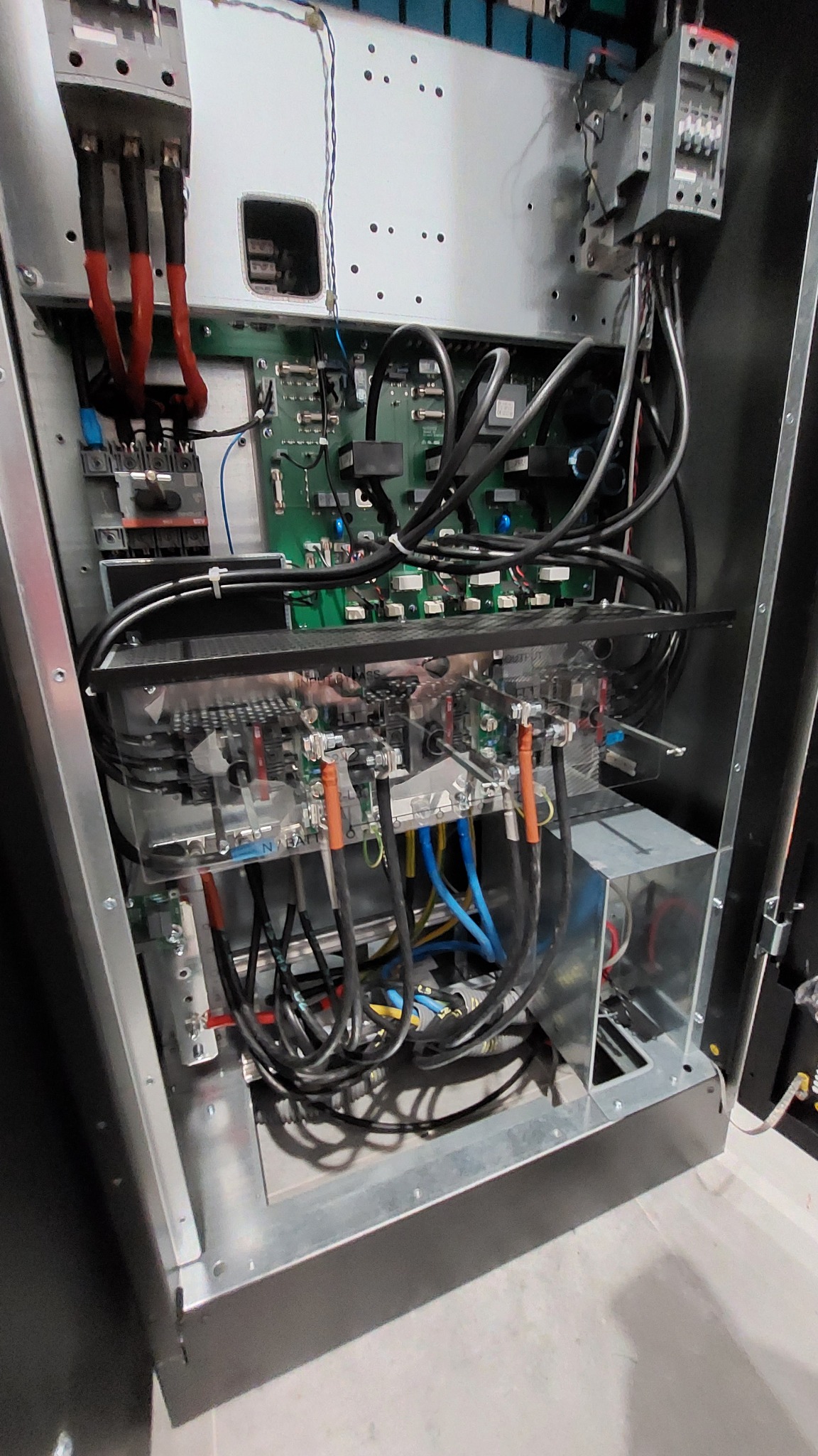 Wnętrze szafy elektrycznej z widocznymi elementami instalacji, przewodami w różnych kolorach i płytkami drukowanymi.