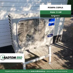 Zewnętrzna jednostka pompy ciepła Haier 5kW, zamontowana na metalowym stelażu przy ścianie budynku z widocznym logo firmy Radtom Eko w lewym dolnym rogu.