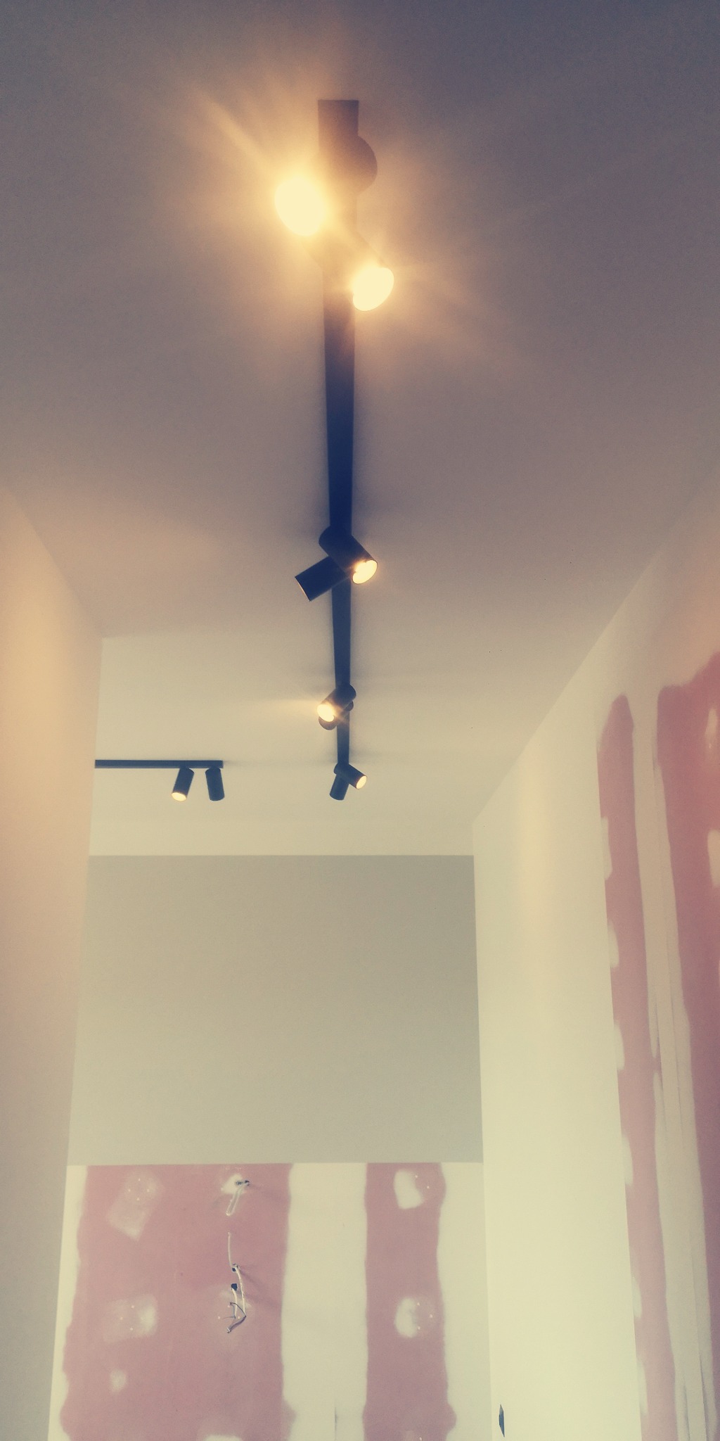 Czarna szyna z reflektorami sufitowymi w nowym pomieszczeniu, widoczne ślady po szpachlowaniu na ścianach.