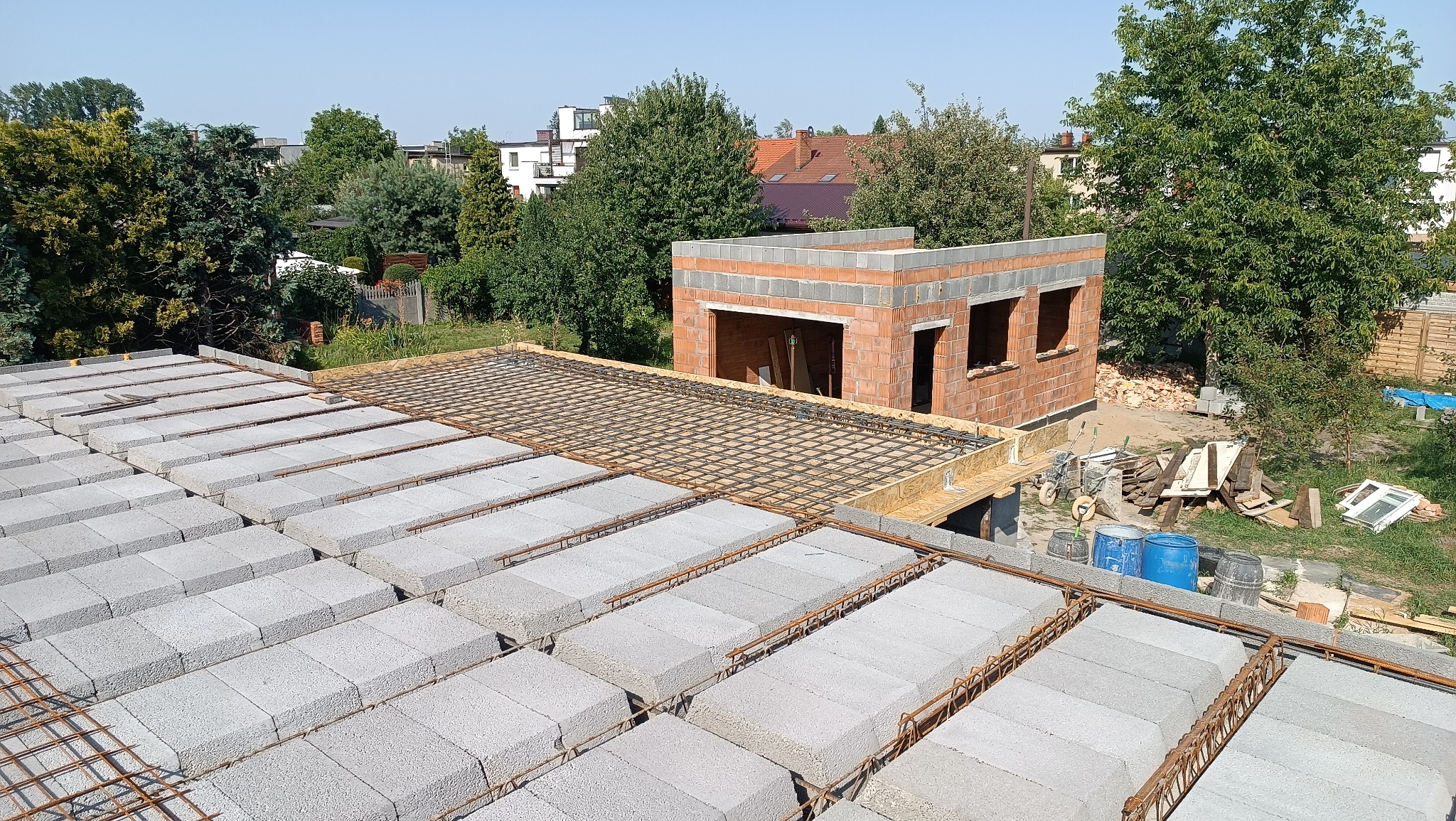 Wznoszenie ścian i stropu Teriva zbrojonego siatką stalową na budowie domu jednorodzinnego w słoneczny dzień.