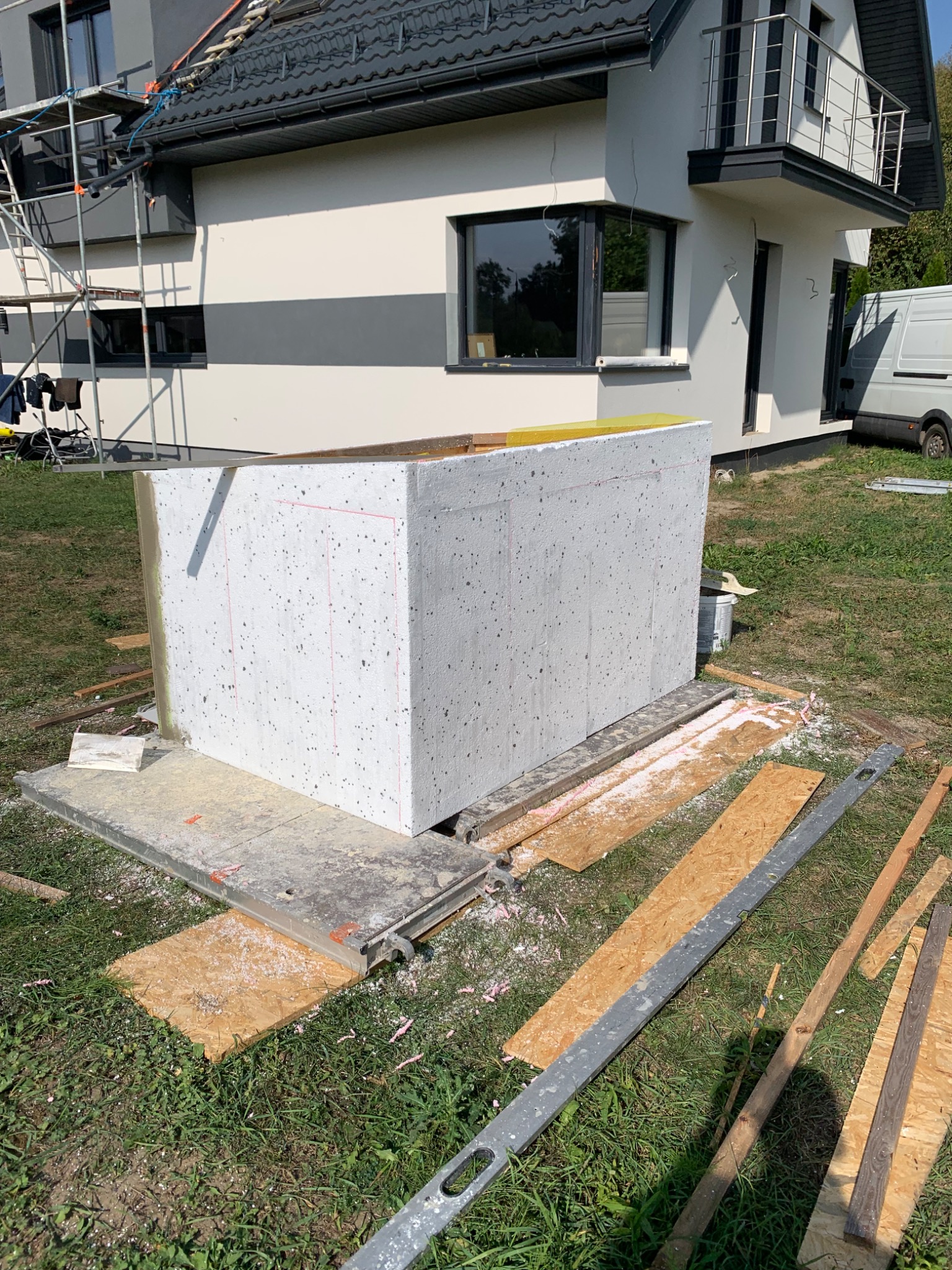 Fragment elewacji domu jednorodzinnego w Karczewie, w trakcie prac przygotowawczych do ocieplenia, widoczne płyty styropianowe z naniesionymi liniami cięcia oraz narzędzia.