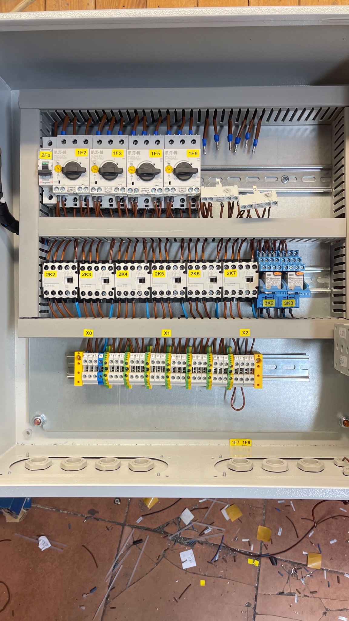 Wnętrze rozdzielnicy elektrycznej z widocznymi zabezpieczeniami, stycznikami i listwami zaciskowymi, okablowanie uporządkowane, widoczne oznaczenia przewodów i komponentów, dół szafy z widocznymi...