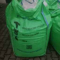 Duży, zielony worek typu big bag z nadrukowanymi symbolami bydła, trzody chlewnej i drobiu, opisany jako 'Przeznaczenie: bydło mleczne i opasowe, trzoda chlewna, drób', z widocznym adresem strony...