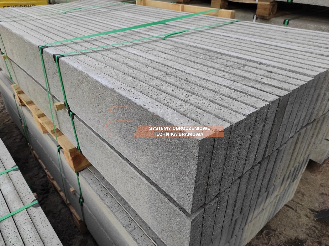Szare płyty betonowe ułożone w stos na palecie, zabezpieczone zielonymi taśmami.