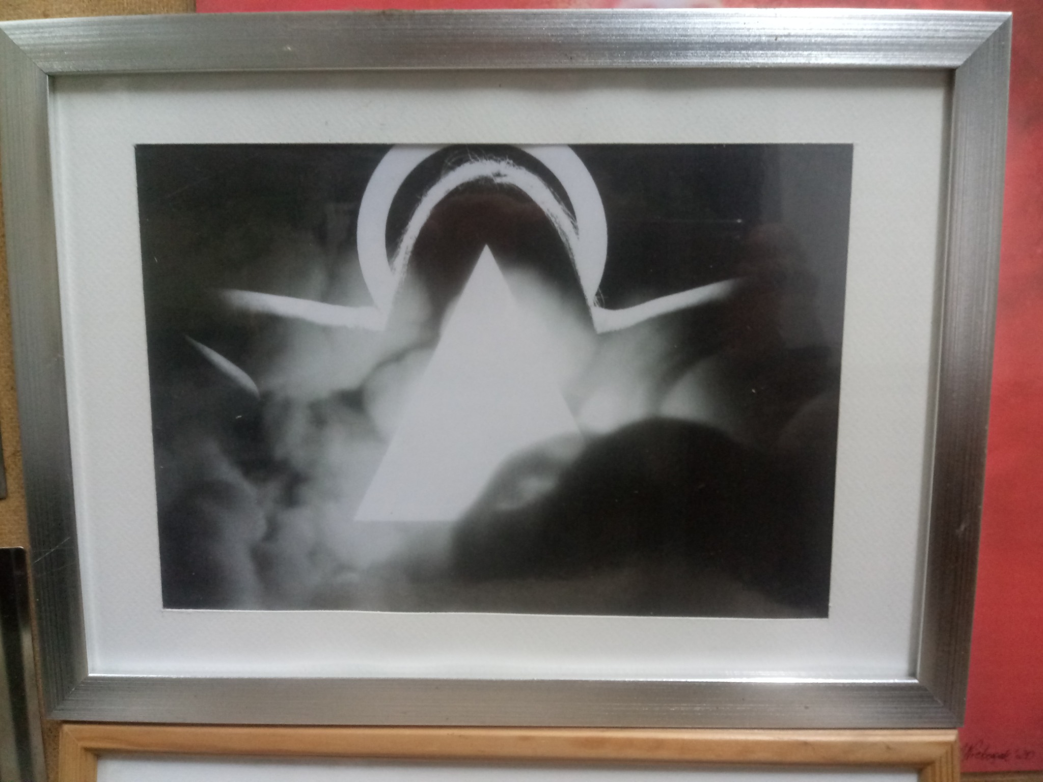 Oprawiona w srebrną ramkę czarno-biała fotografia abstrakcyjna z motywem trójkąta i łuków na tle przypominającym dym.