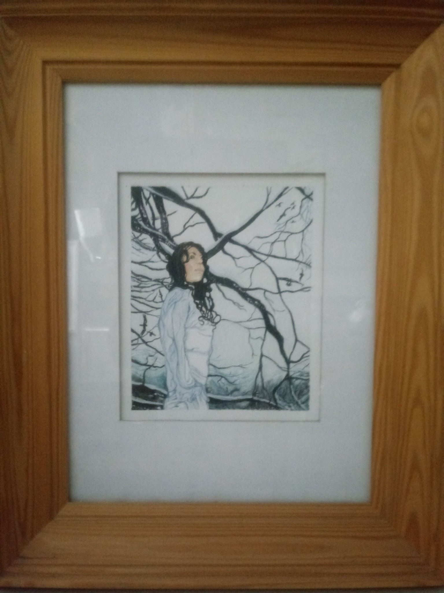 Oprawiony rysunek przedstawiający kobietę na tle drzewa o splątanych gałęziach, w jasnej tonacji, z drewnianą ramą.