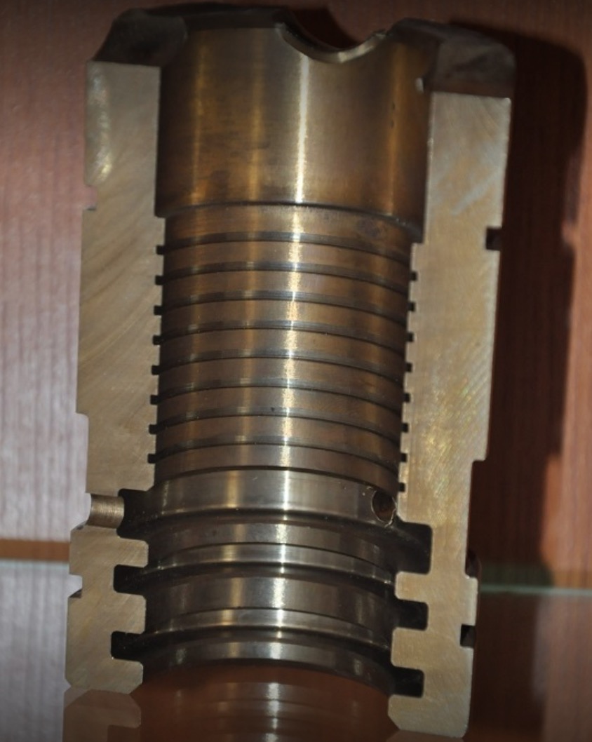 Przekrój elementu metalowego z widocznymi pierścieniami i rowkami, wykonany z brązu, prezentujący precyzyjną obróbkę.