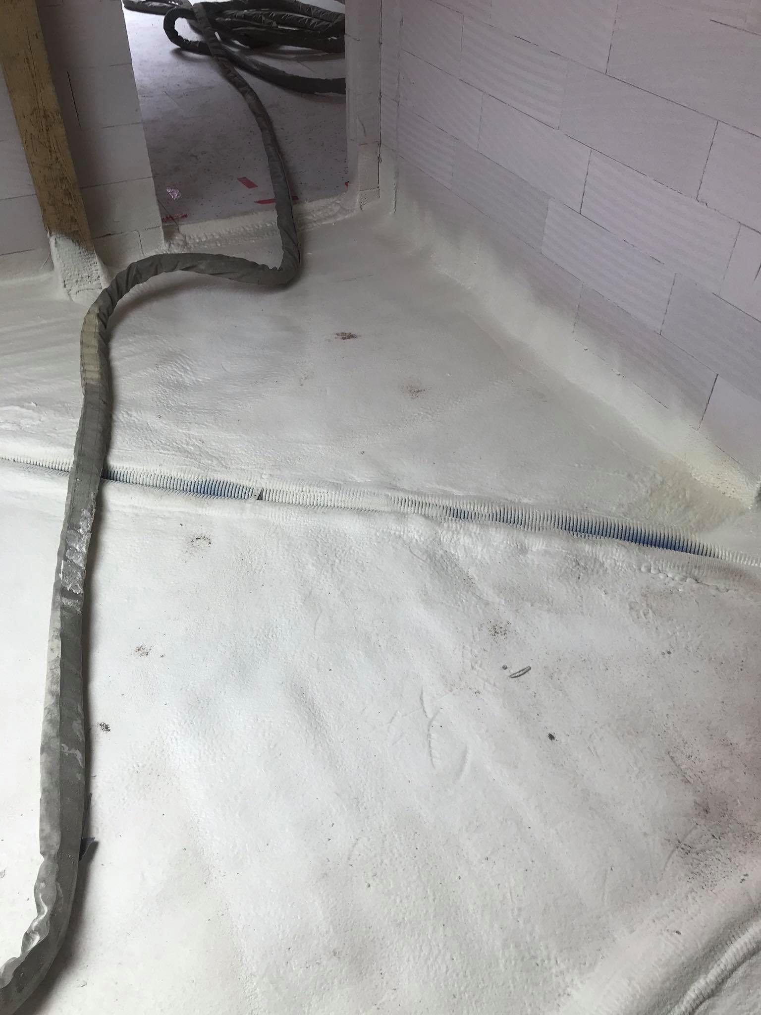 Poddasze po natrysku pianki poliuretanowej, widoczny szary wąż do aplikacji pianki i fragment instalacji elektrycznej w peszlu.