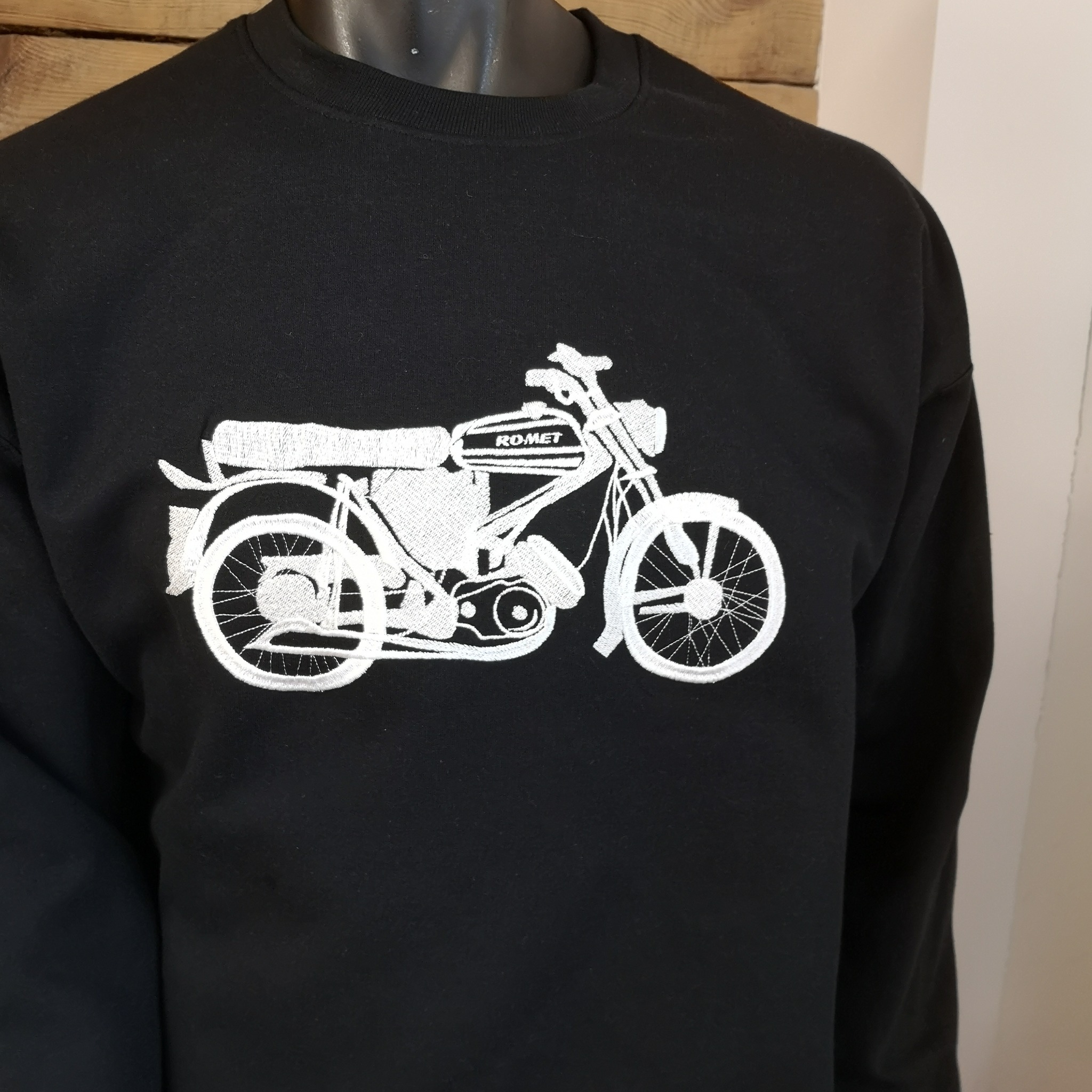 Czarna bluza z białym haftem przedstawiającym motocykl marki Romet, widoczna na manekinie.