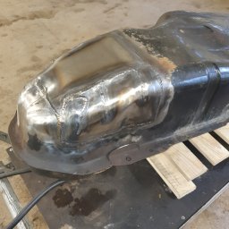 KIERTOM - Naprawiony, spawany zbiornik paliwa na stole warsztatowym z widocznymi śladami spawania i naprawy.