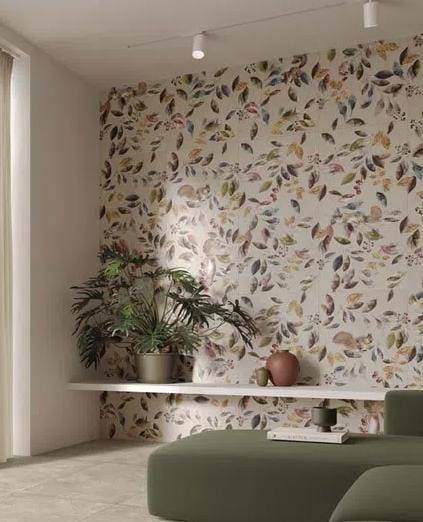 Ściana wykończona płytkami z motywem liści, oświetlenie punktowe, minimalistyczna półka z rośliną doniczkową i element sofy w neutralnej tonacji.