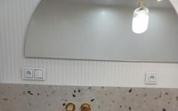 Nowoczesna łazienka: lustro z zaokrąglonym blatem, złota armatura i subtelne oświetlenie. Minimalistyczny design z dbałością o detale.