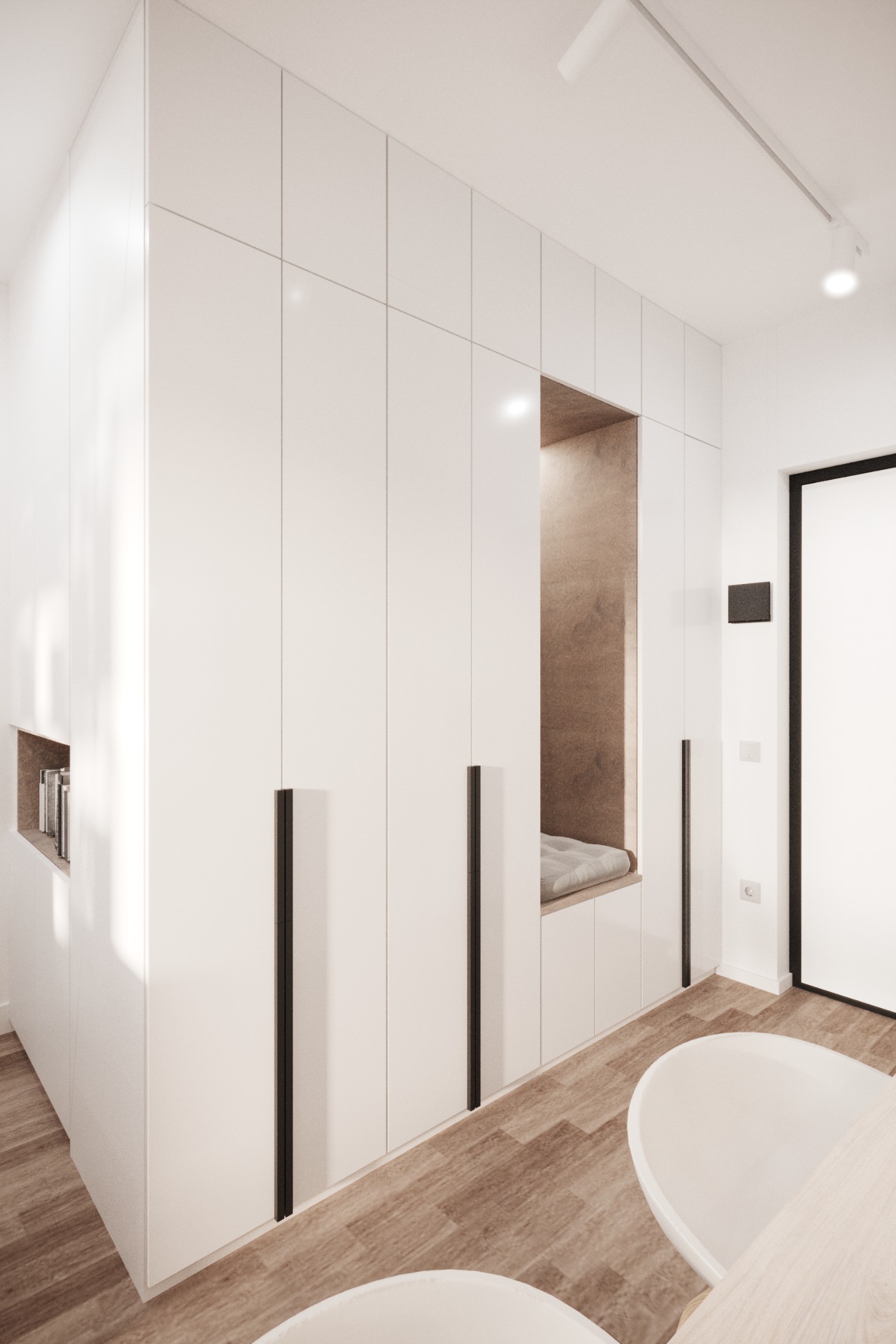 Minimalistyczna zabudowa szafy wnękowej z siedziskiem i półką na książki, białe fronty z czarnymi uchwytami, drewnopodobna podłoga, nowoczesne oświetlenie sufitowe.