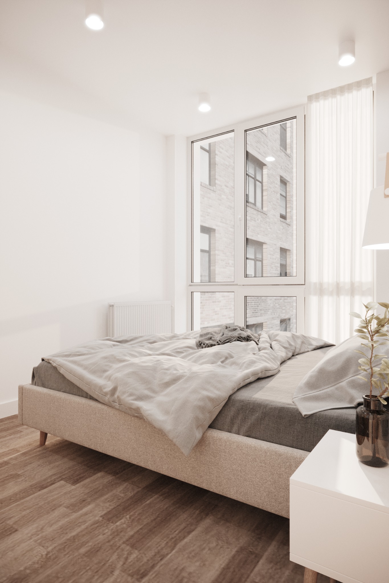 Jasne wnętrze sypialni z łóżkiem na tle okna z widokiem na budynek mieszkalny, parkiet na podłodze, biała szafka nocna z wazonem i rośliną.