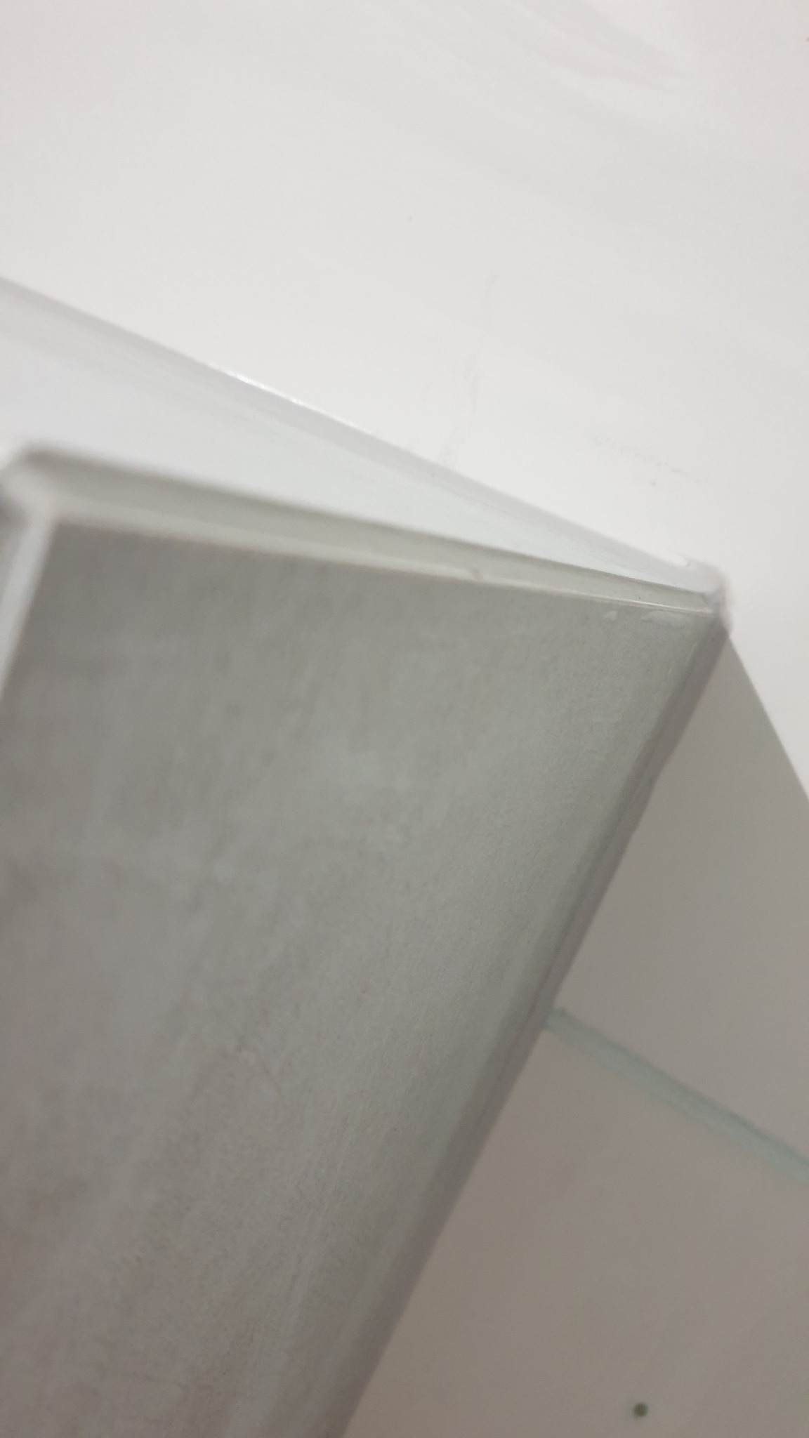 Fragment ściany po nałożeniu gładzi, widoczna listwa wykończeniowa przy suficie, ujęcie z dołu.