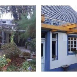 Dom z białą elewacją i niebieskimi akcentami, z drewnianą pergolą nad oknami, widok z ogrodu z bujną roślinnością.