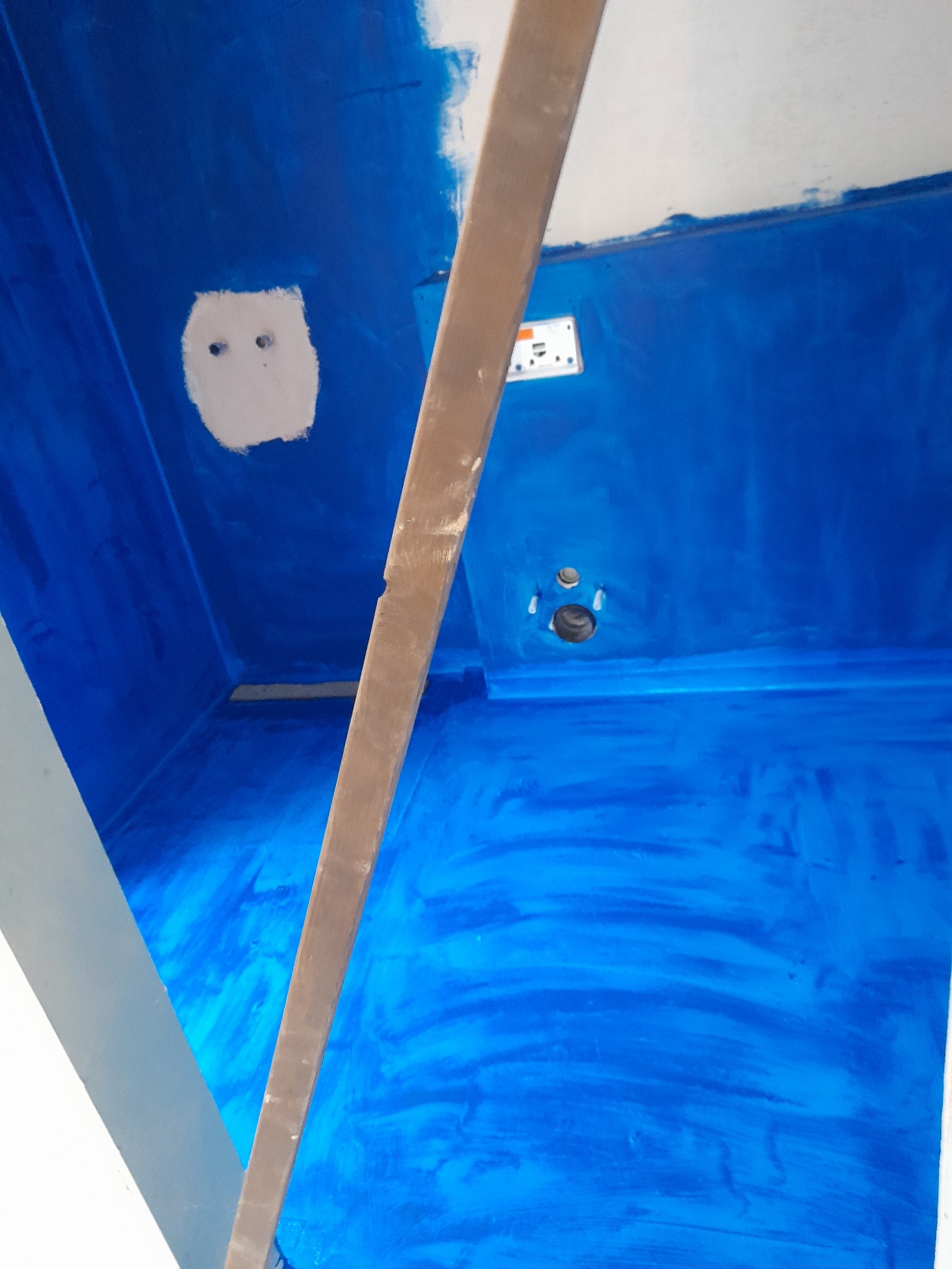 Niebieskie wnętrze w trakcie malowania z widoczną instalacją elektryczną i częściowo zakrytym drewnianym elementem konstrukcyjnym.