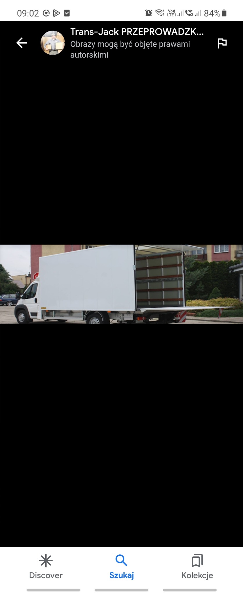 Biała furgonetka z otwartymi drzwiami przestrzeni ładunkowej, zaparkowana w Żelazkowie na tle zieleni i budynków mieszkalnych.