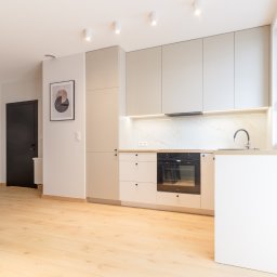 home advisor - Jasna kuchnia w nowoczesnym stylu z drewnianą podłogą, białymi szafkami, marmurowym blatem i czarną armaturą, oświetlona punktowymi lampami sufitowymi i listwą LED pod szafkami górnymi.