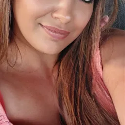 Portret kobiety z brązowymi włosami i makijażem oczu, ubrana w r&oacute;żową koronkową sukienkę.