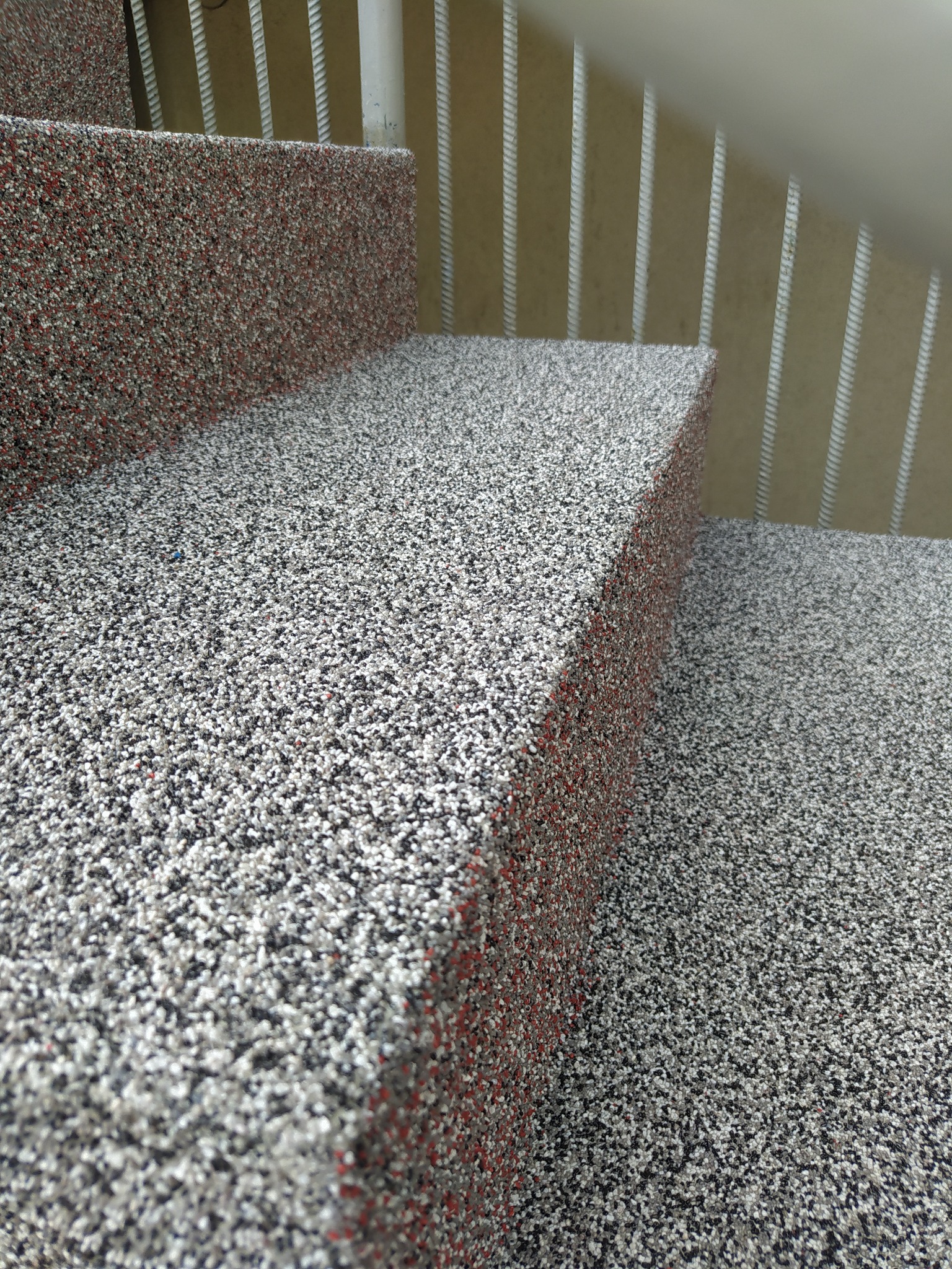 Schody wykończone żywicą epoksydową z kolorowym kruszywem, widoczne poręcze schodowe.