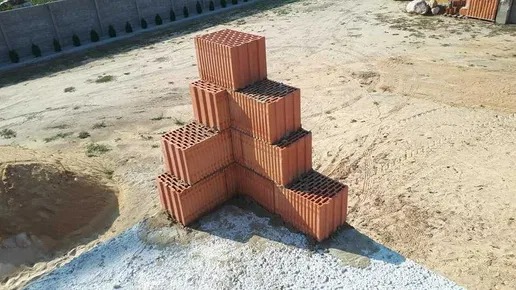 Układanka z czerwonych bloczków ceramicznych na przygotowanym fundamencie, widok z góry, teren budowy.