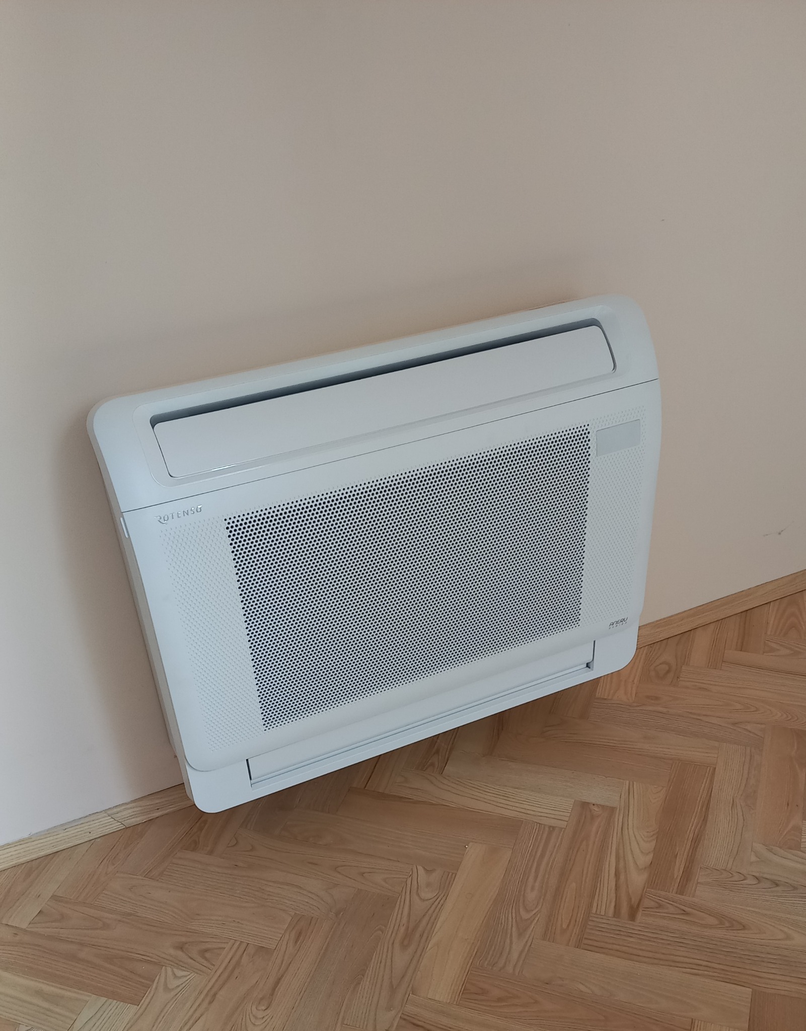 Ścienna jednostka klimatyzacyjna Rotenso zamontowana w domu w Gliwicach, widoczna na tle beżowej ściany i parkietu ułożonego w jodełkę.