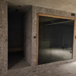 Nowoczesna łazienka w trakcie wykańczania, widoczna kabina prysznicowa z szklanymi drzwiami w drewnianej ramie oraz wnęka z półką i prysznicem, ściany i podłoga wyłożone płytkami imitującymi...