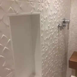 Białe, trójwymiarowe płytki w łazience z wnęką w ścianie i chromowaną armaturą.