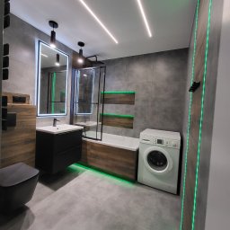 Gold Time Mykola Naboka - Nowoczesna łazienka z szarymi płytkami, drewnopodobnymi akcentami, podświetleniem LED, czarną armaturą i pralką Bosch.