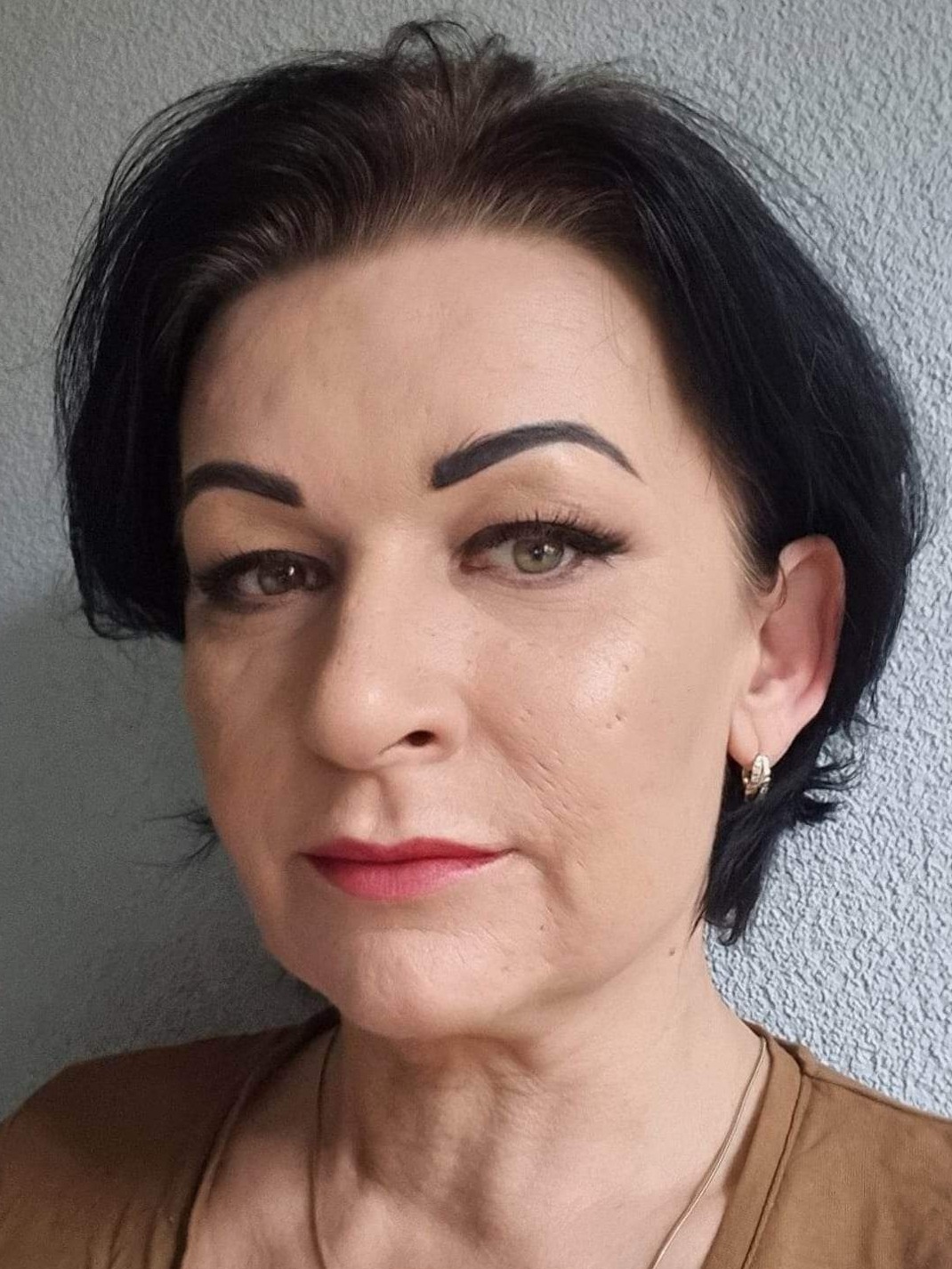 Portret kobiety z ciemnymi włosami, wyrazistymi brwiami i delikatnym makijażem ust, prezentującej efekt zabiegu kosmetycznego.