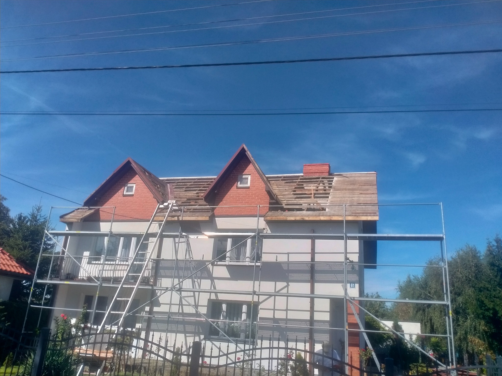 Dom w Łowiczu w trakcie wymiany poszycia dachowego, widoczne rusztowania i częściowo odsłonięta konstrukcja dachu.