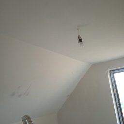 Mariusz Godzina - Poddasze z oknem po szpachlowaniu, widoczne niedoskonałości przed malowaniem, drabina w rogu, surowa żarówka