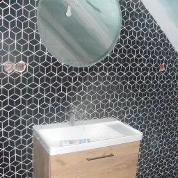 Umywalka z szafką w łazience z czarno-białymi, geometrycznymi płytkami na ścianie pod skosem, okrągłe lustro z żarówką na kablu.