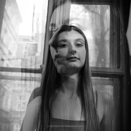 trybmanualny.pl - Czarno-biała fotografia portretowa młodej kobiety z nałożoną ekspozycją twarzy mężczyzny, stojącej na tle okna.