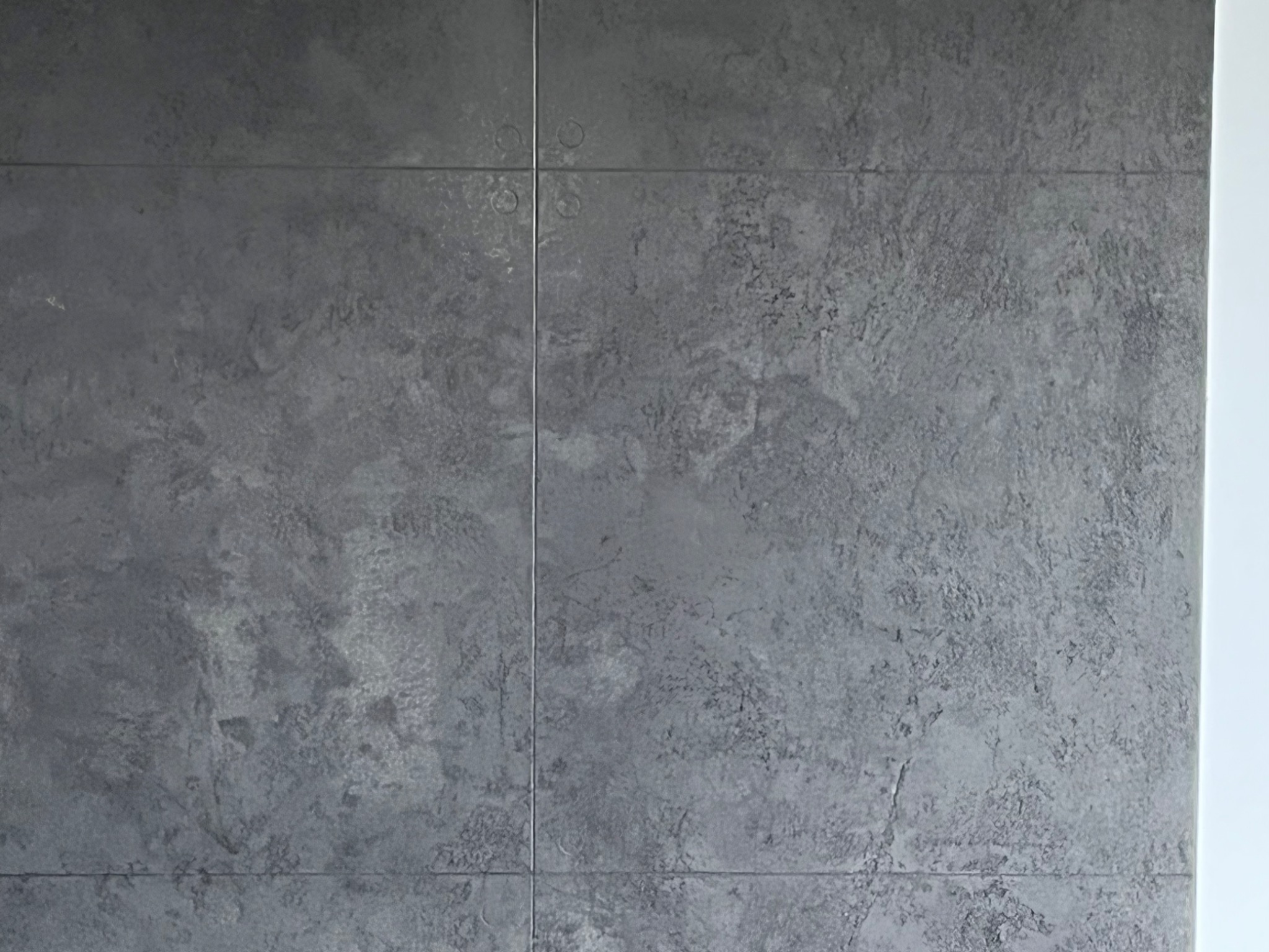 Szara ściana wykończona płytkami imitującymi beton w Łańcucie, widoczne fugi i struktura powierzchni.