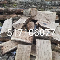 Stos pociętego drewna z widocznym numerem telefonu nałożonym na zdjęcie, w tle kora i resztki śniegu.