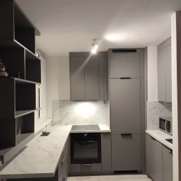 J&K Meble na Wymiar JANUSZ RYCHLICA - Nowoczesna kuchnia w szarościach z blatem imitującym marmur. Otwarte półki i zabudowa po sufit. Minimalistyczne uchwyty i oświetlenie punktowe.