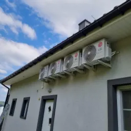 Elewacja domu w Andrychowie z zamontowanymi czterema klimatyzatorami LG, widoczna drabina i samochód dostawczy w tle.