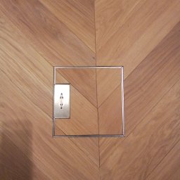 DAS the art of real estate sp. zo.o. - Parkiet ułożony we wzór jodełki francuskiej w Gdańsku, z widoczną metalową klapą rewizyjną, idealnie wkomponowaną w drewnianą podłogę.