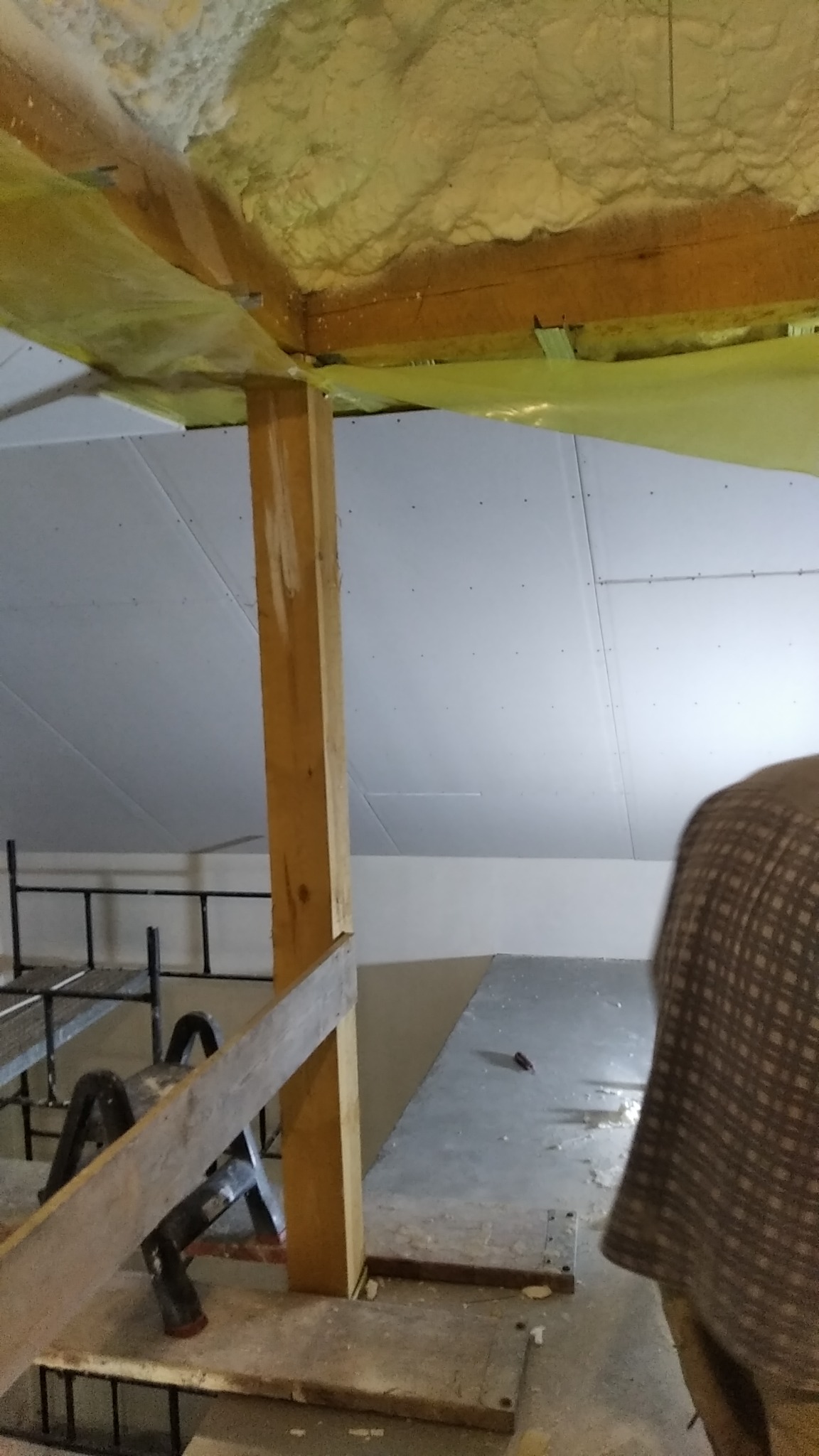 Poddasze w trakcie ocieplania pianą PUR, widoczne płyty karton-gips na skosach, drewniana konstrukcja i fragment rusztowania.