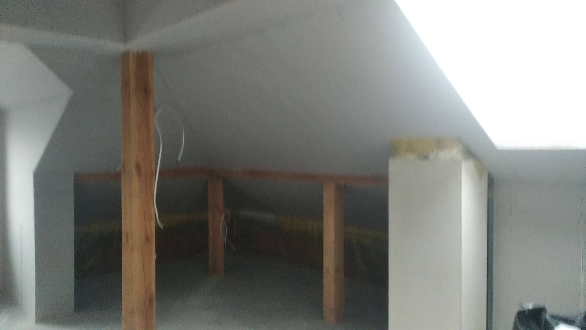 Poddasze w Żorach w trakcie adaptacji, widoczne drewniane belki konstrukcyjne, częściowo zamontowana izolacja i płyty gipsowo-kartonowe na skosach.