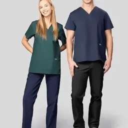 Dwoje uśmiechniętych modeli prezentuje odzież roboczą: kobieta w zielonym komplecie i białych trampkach, mężczyzna w granatowym komplecie i białych butach, na jasnoszarym tle.